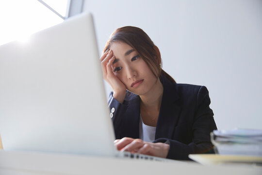 職場のデスクでパソコンを見て暗い表情をする女性