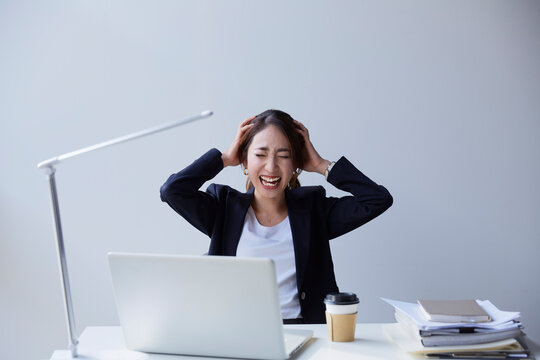 職場のデスクで頭を抱える女性