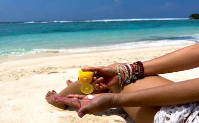 Woman hand  with sunscreen cream on the sand beach as applying moisturizing lotion on .Skin care protection concept
