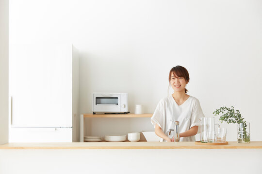 シンプルでナチュラルなオープンキッチンで微笑む女性