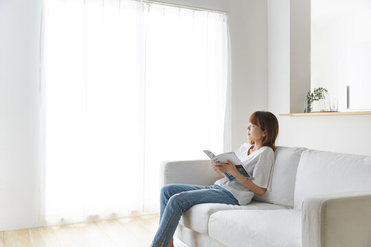 白いソファで雑誌を持ってくつろぐ女性
