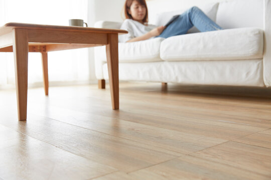 白いソファで雑誌を見てくつろぐ女性の近くの床アップ