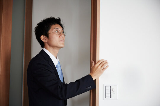 壁に手をかけているスーツを着た男性