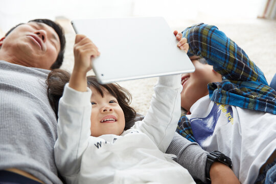 リビングで寝転がりタブレット端末を使う家族