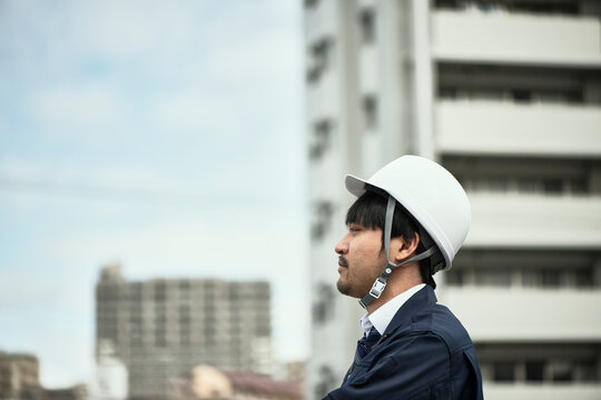 遠くを見ている作業服の男性