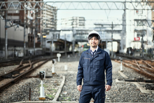 線路に立つ作業服とヘルメットの男性