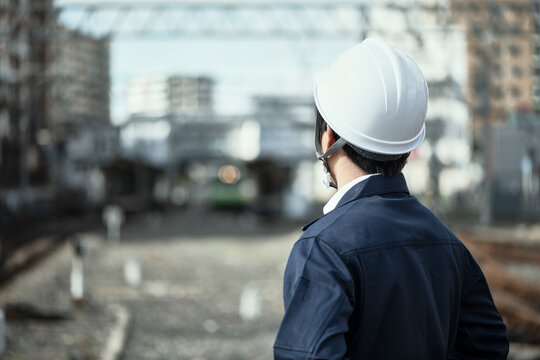 線路に立つ作業服とヘルメットの男性