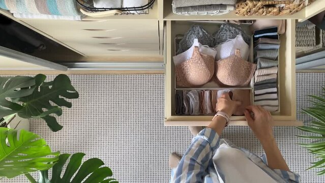 An unidentified neat housewife takes underwear, socks, panties and a bra from a closet drawer. The concept of organization, storage and order. 