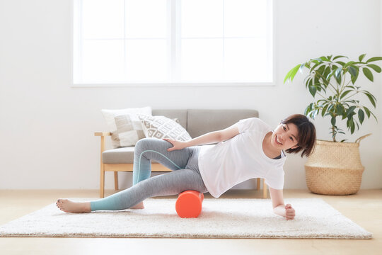 室内の床でストレッチポールを使ってストレッスル女性