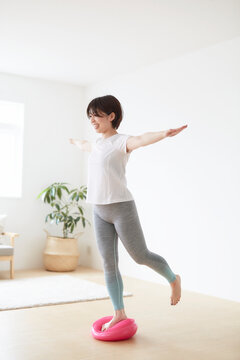室内でバランスディスクを使ってトレーニングする女性