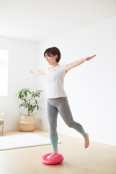 室内でバランスディスクを使ってトレーニングする女性