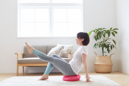 室内でバランスディスクを使ってトレーニングする女性