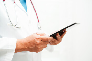 Asian woman doctor holding mobile phone or tablet for search method of treatment patient in hospital.