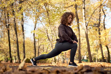 Red head woman stretching before jogging in the park