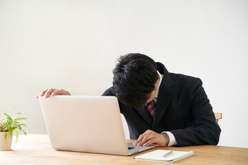 パソコンでのオンライン面接で頭を下げる男子の就活生