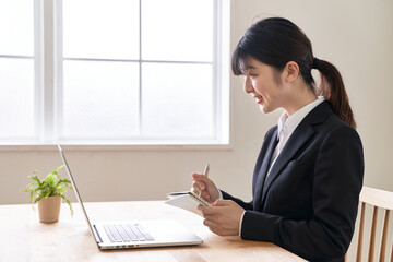 パソコンでオンライン面接でメモを書き留める女子の就活生