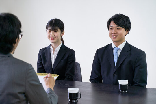 集団面接で面接官と会話をする男女の就活生