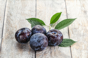 Raw purple plums heap with leaves