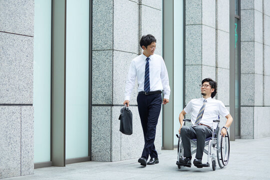 オフィス街で車椅子の男性と話すスーツの男性