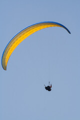 A man flies on paraplane. Clear blue sky.