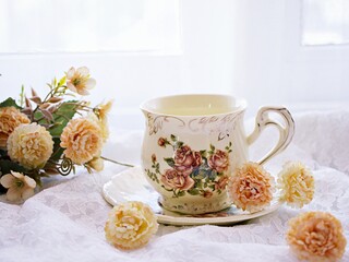Antique cup of tea with saucer ,yellow orange rose flowers background ,porcelain vintage style ,old English coffee cup still life for wallpaper ,romance roses backgrounds 