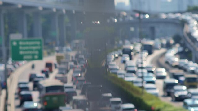 A blurred image of Jakarta's urban traffic density with lots of round bokeh. Depicts high pollution, heat, congestion and chaos. Taken with a telephoto lens with a panning motion