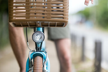 avant d'un vélo, bicyclette avec un phare lumière, porte bagage avant, frein et roue. Un homme est sur le vélo en short © lamurebenjamin
