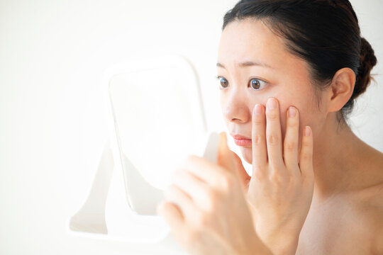 鏡で自分の顔を見ている女性