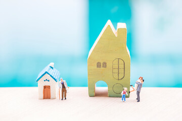 Miniature people with house model over blurred background, family house and retirment home, property business