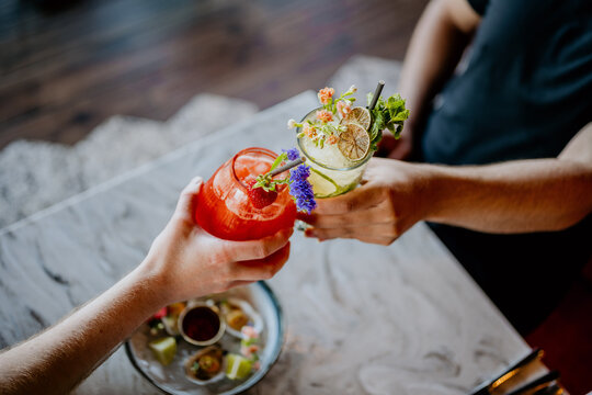 People toasting with different cocktails, made of cucumber and strawberry with oyster platter on table in restaurant