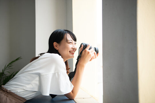 一眼レフカメラを構えて笑っている女性