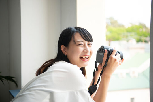 一眼レフカメラを構えて笑っている女性