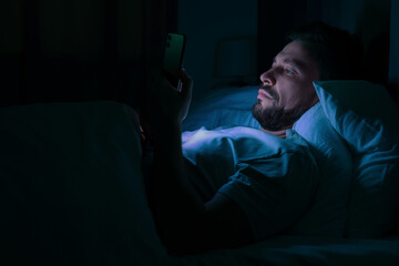Man using smartphone in bed at night. Internet addiction