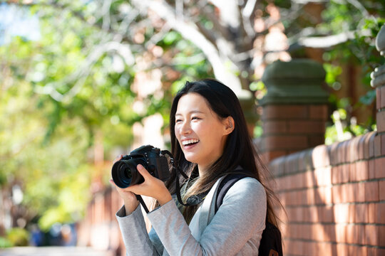 一眼レフのカメラを構えて笑っている女性
