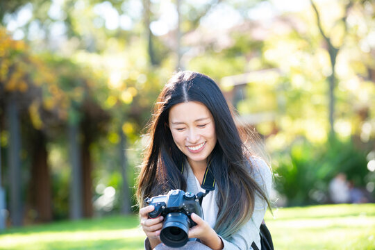 一眼レフのカメラを持って笑っている女性