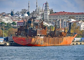 Foto op Plexiglas Schipbreuk closeup of wreck of old rusty ship with industry in the background  in Turkey