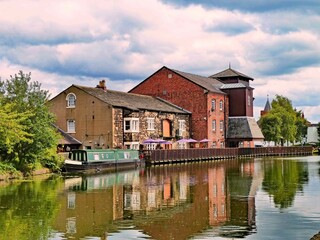 Picturesque view of the Leeds Liverpool canal in Leigh Greater Manchester with barge and cloudy sky
