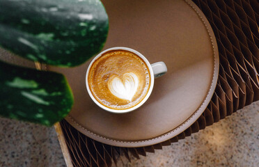 Close up white coffee cup with heart shape latte art on wood tab