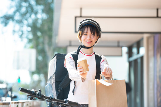 デリバリーの商品を差し出している配達員の女性