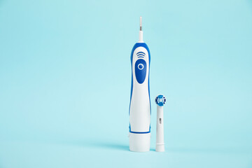 Electric toothbrush on light blue background, space for text