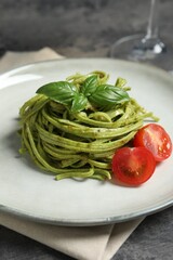 Tasty tagliatelle with spinach and tomatoes served on grey table, closeup. Exquisite presentation of pasta dish