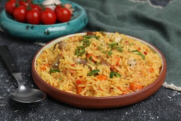 Delicious pilaf with meat served on black textured table, closeup
