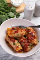 Delicious stuffed cabbage rolls cooked with homemade tomato sauce on white marble table