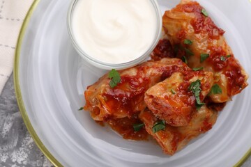 Delicious stuffed cabbage rolls served with sour cream on grey table, top view