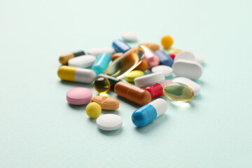 Pile of different pills on mint background, selective focus