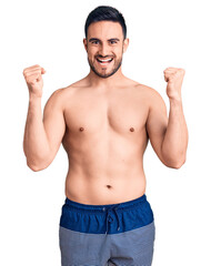 Fototapeta premium Young handsome man wearing swimwear screaming proud, celebrating victory and success very excited with raised arms