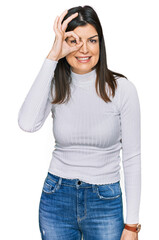 Fototapeta premium Beautiful brunette woman wearing casual clothes doing ok gesture with hand smiling, eye looking through fingers with happy face.