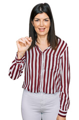 Obraz na płótnie Canvas Beautiful brunette woman wearing striped shirt showing and pointing up with fingers number three while smiling confident and happy.