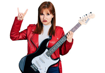 Fototapeta premium Redhead young woman playing electric guitar doing rock gesture depressed and worry for distress, crying angry and afraid. sad expression.