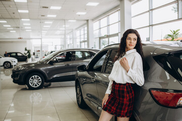 a beautiful woman is looking for a car in a car dealership